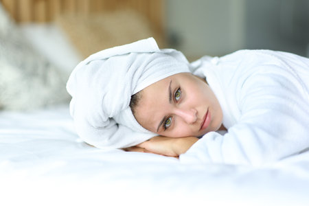 Beauty woman with green eyes looks at camera lying on the bedの写真素材