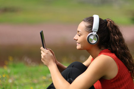 Profile of a happy woman in the mountain listening to music with headphones and phoneの写真素材
