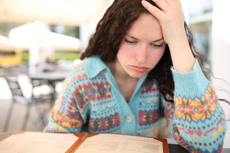 Front view of a stressed woman reading menu in a restaurantの写真素材