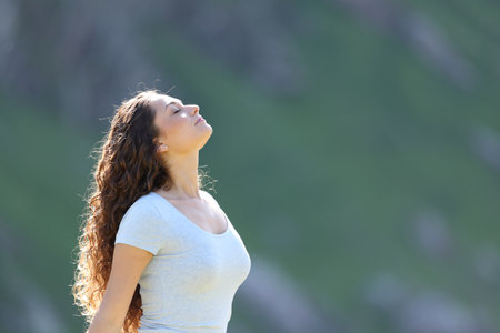 Side view portrait of a woman breathing fresh air in the mountain a sunny dayの写真素材