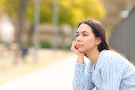 Relaxed woman contemplating views sitting in a parkの写真素材