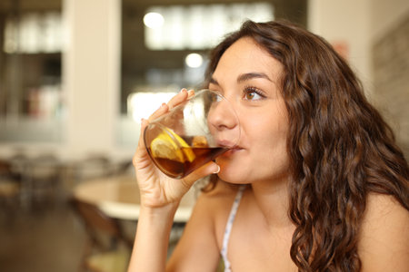 Happy woman drinking soda looking away in a barの写真素材