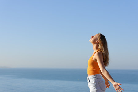 Side view portrait of a teen breathing fresh air on the beach with horizon in the backgroundの写真素材