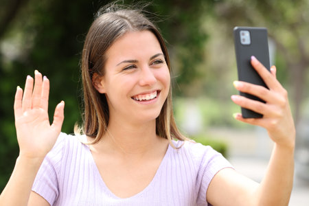 Happy teen greeting in a video call with smart phoneの写真素材