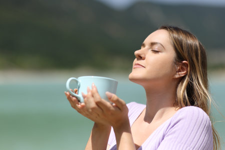 Woman in nature smelling coffee mug and relaxingの写真素材