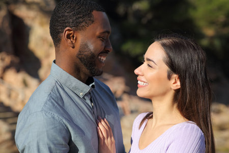 Profile of an interracial couple in love looking at each other outdoorsの写真素材