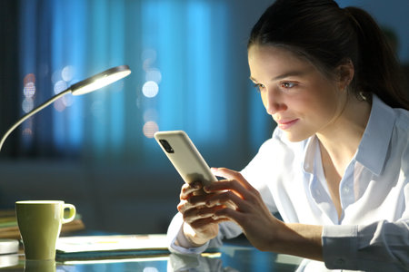 Entrepreneur in the night checking cell phone in a deskの写真素材