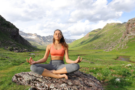Front view full body portrait of a yogi doing yoga exercise in a mountain valleyの写真素材