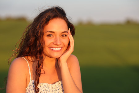 Happy beautiful woman posing in a field at sunsetの写真素材