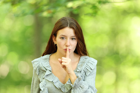 Front view portrait of a woman who is asking for silence in a forestの写真素材