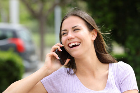Teen laughing during a phone call in a parkの写真素材