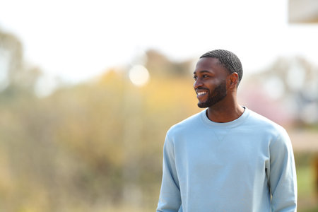 Happy black man walking looking at side in a parkの写真素材