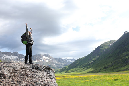 Excited hiker celebrating raising arms in the mountainの写真素材