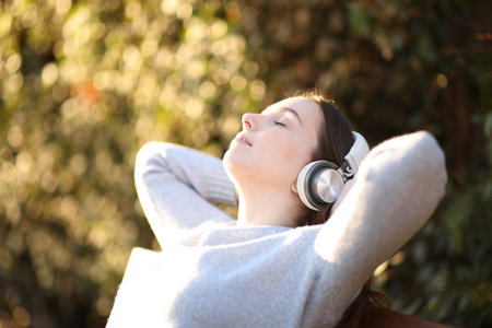 Woman resting listening to music sitting on a bench in a parkの写真素材