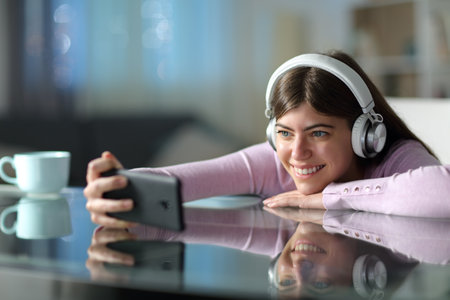 Happy teen watching media on phone in the night at homeの写真素材