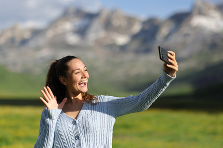 Happy tourist in nature having video call with phoneの写真素材