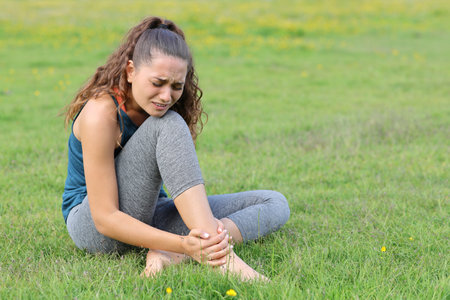 Yogi suffering ankle ache sitting on the grass ather exercise accidentの写真素材