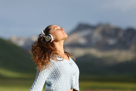 Relaxed woman meditating in nature listening audio guide with headphonesの写真素材