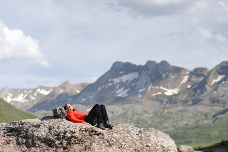 Hiker resting on the top of a mountain lying on a rockの写真素材