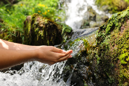 Close up of a woman hands catching water from creekの写真素材