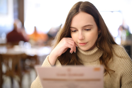 Front view portrait of a woman reading menu in a restaurantの写真素材
