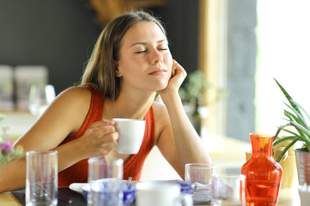Teen relaxing sitting in a restaurant at breakfast holding coffee cupの写真素材