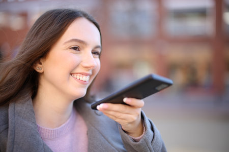 Happy woman in winter dictating message on phoneの写真素材