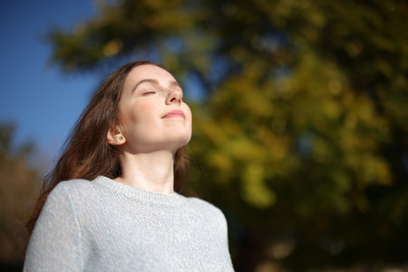 Relaxed woman breathing fresh air in nature on a sunny dayの写真素材