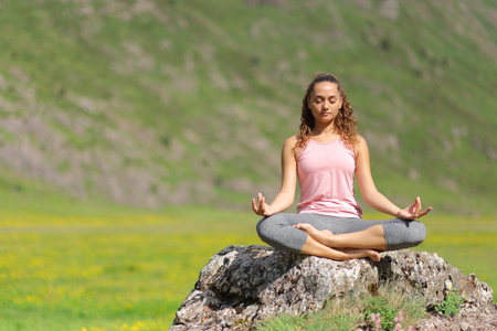Front view proportion of a yogi doing yoga on a rock in the mountainの写真素材