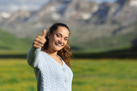 Happy casual ecotourist gesturing thumb up in the mountainの写真素材