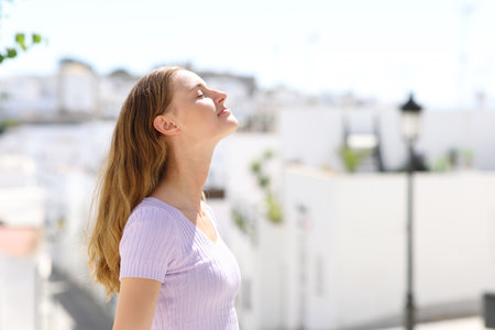 Relaxed woman breathing fresh air in summer vacation in a white spanish townの写真素材