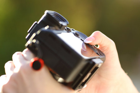 Close up of a photographer hand setting mirrorless camera in a parkの写真素材