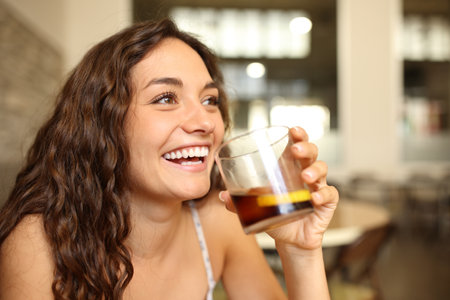 Funny woman laughing holding soda glass in a barの写真素材