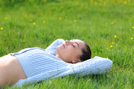 Casual woman relaxing lying on the grass in natureの写真素材