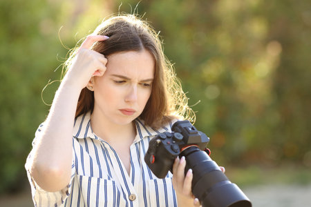 Upset photographer checking photos on mirrorless camera in a parkの写真素材