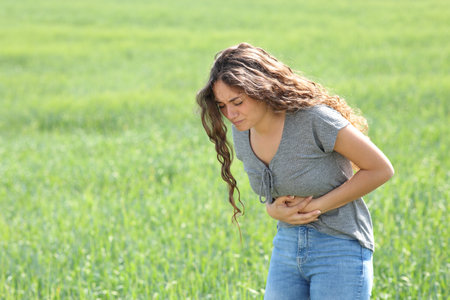 Woman suffering belly ache complaining in a fieldの写真素材