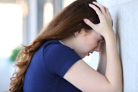 Side view portrait of a sad woman complaining leaning on a wallの写真素材