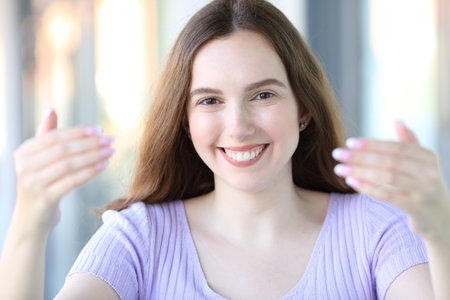Front view portrait of a happy woman smiling gesturing come here in the streetの写真素材