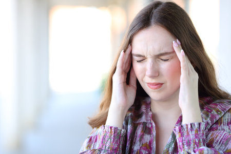 Stressed woman suffering migraine attack touching temple in the streetの写真素材
