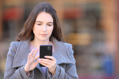 Front view portrait of a serious woman using smart phone in winterの写真素材