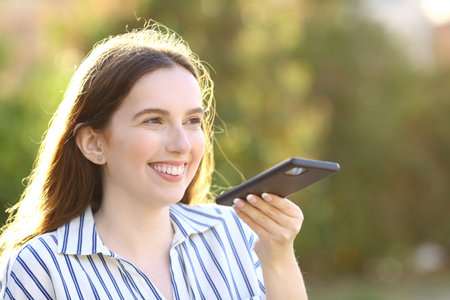 Happy woman dictating message on cell phone in a parkの写真素材