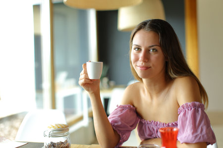 Happy teen looks at you in a restaurant holding coffee cupの写真素材