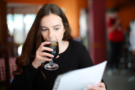 Serious woman drinking and reading menu sitting in a barの写真素材