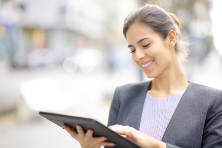 Happy executive using tablet smiling standing in the streetの写真素材
