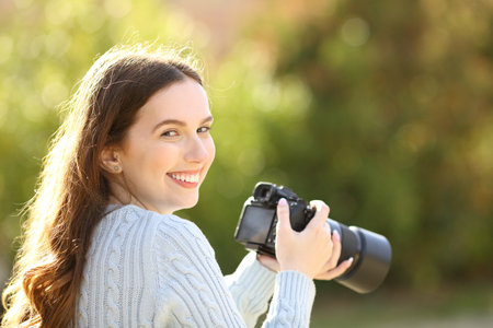 Happy photographer in a park looks at you holding cameraの写真素材