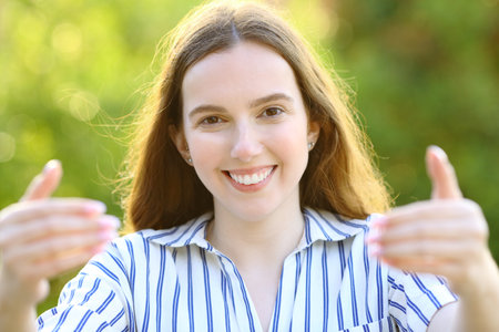 Front view portrait of a happy woman inviting to eat in a parkの写真素材