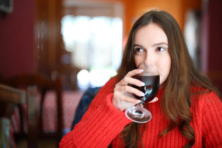 Woman in red sweater drinking soda sitting in a barの写真素材