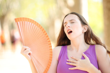 Woman stressing fanning on summer hot day in a parkの写真素材