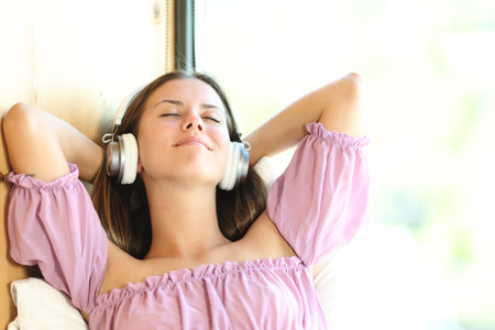 Front view portrait of a relaxed teen listening to music with headphones indoors in a houseの写真素材
