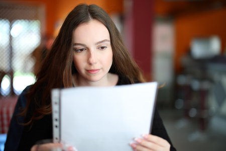 Front view portrait of a serious woman reading menu in a restaurantの写真素材